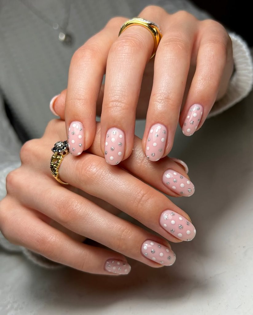 Oval pink nails with white polka dots and silver glitter accents
