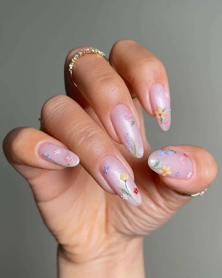 Almond shaped nails with pearlescent pink base and tiny multicolored flower designs