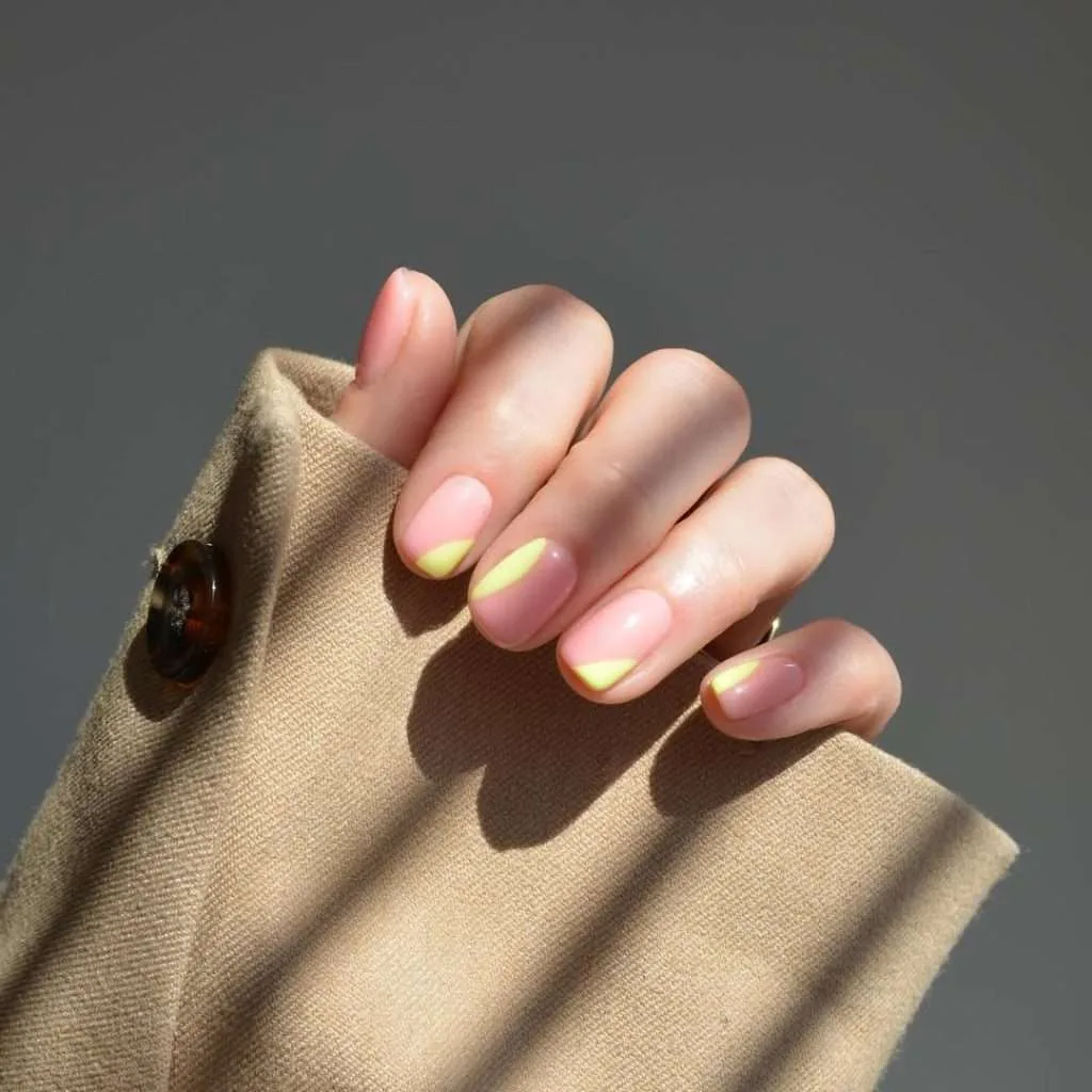 Short nails with pink and nude base and diagonal yellow accent design