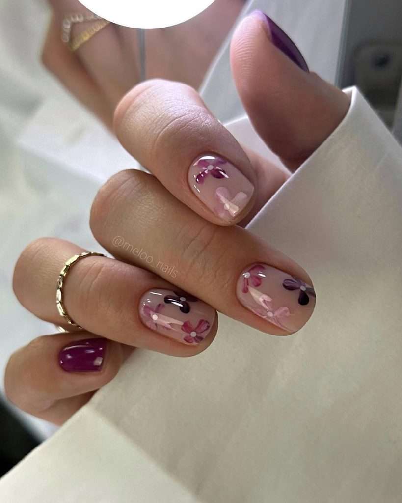 Short square nails with nude base, pink and plum floral art, and solid plum accent nails