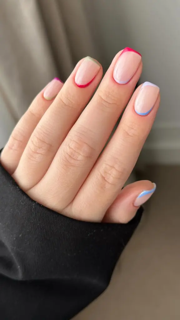 Short summer nails with transparent nude base featuring thin colorful diagonal lines and edge accents in different bright hues including pink, green and blue
