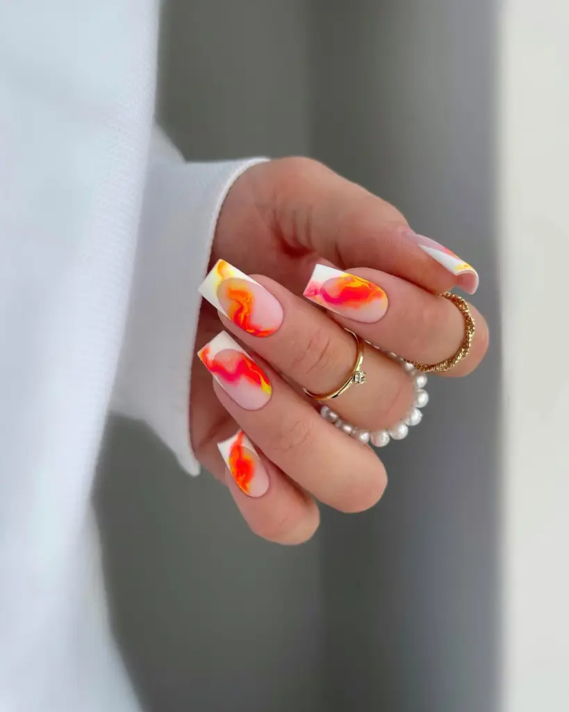  Square summer nails with sheer pink base featuring orange, pink and yellow marble design with white French tips
