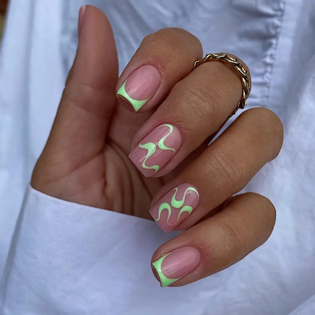 Short square summer nails with pink base featuring neon green abstract swirl designs on some nails and geometric French tips on others