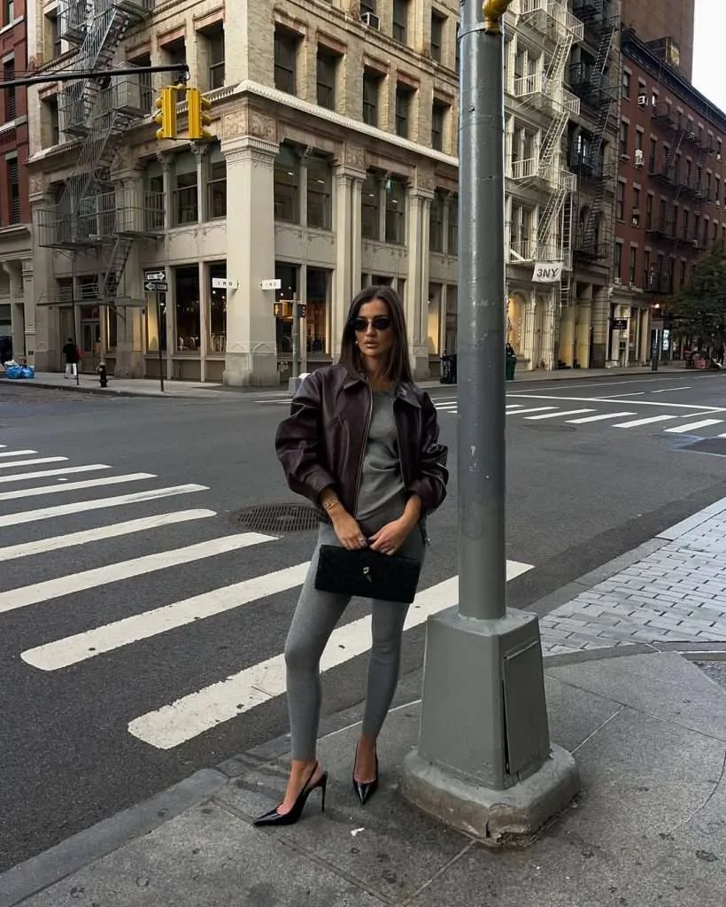  Casual chic spring date night outfit with burgundy leather jacket, gray sweater, matching leggings, black pointed heels and clutch