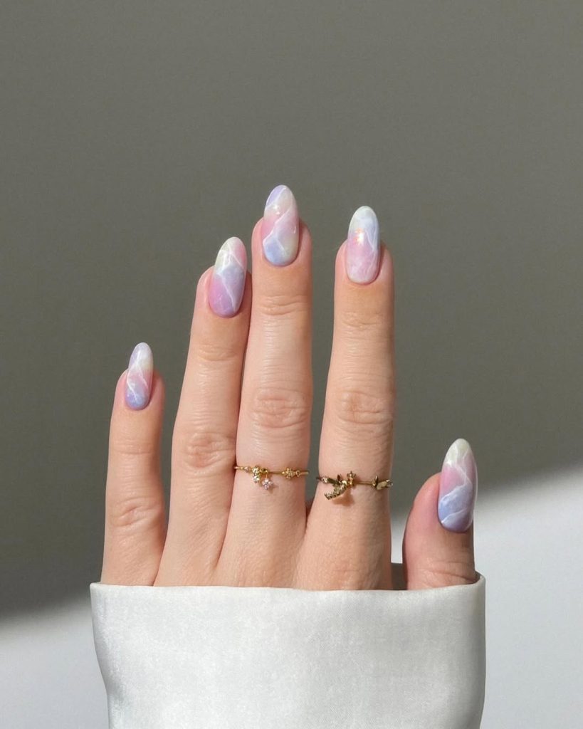 Almond shaped nails with pastel pink, blue and white marble effect design
