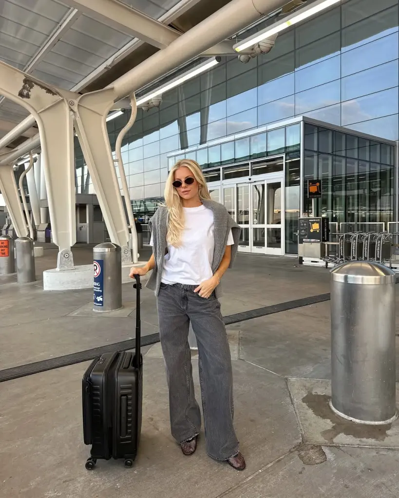 Minimalist airport outfit with white t-shirt, gray cardigan, charcoal wide-leg jeans, small round sunglasses and mesh flats