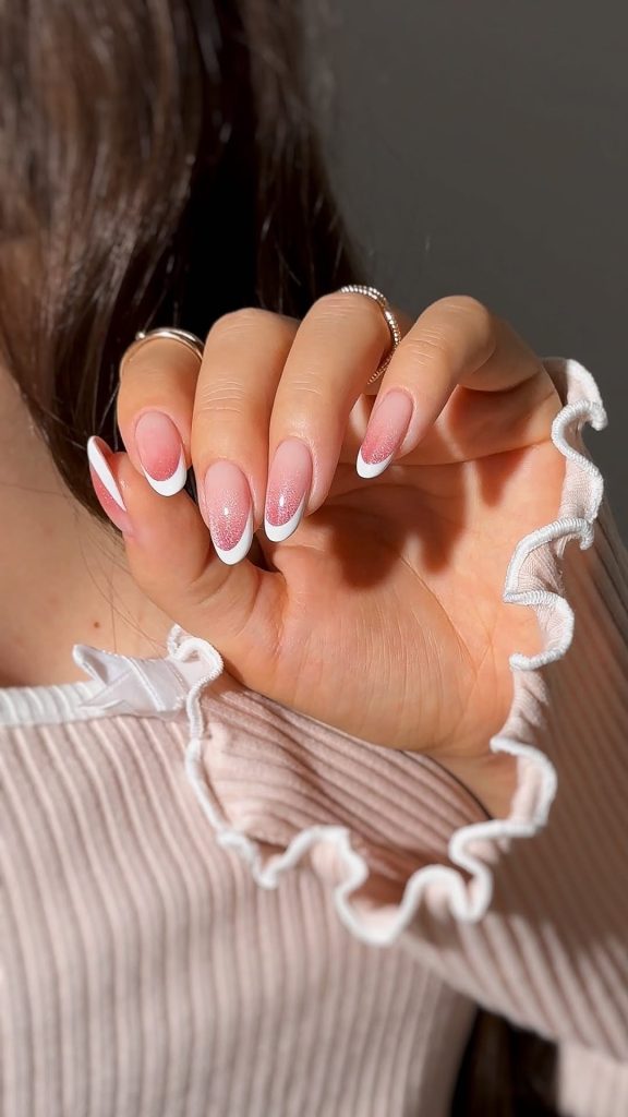 Almond shaped nails with pink base, white French tips and pink glitter gradient between colors