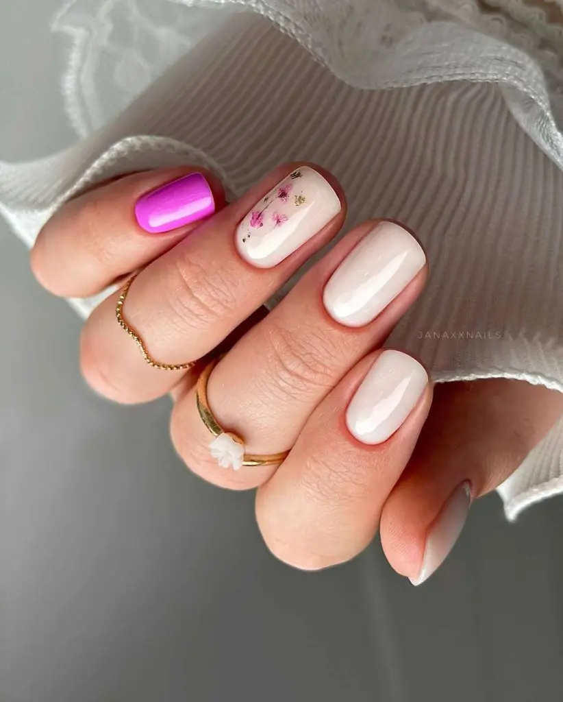 Short square nails in pearl white with magenta accent nail and tiny pink flower art
