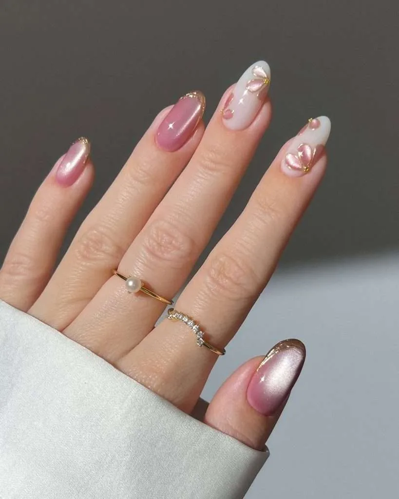 Almond shaped nails featuring pink cat eye finish with gold tips and magnetic petal designs outlined in gold for luxury spring manicure
