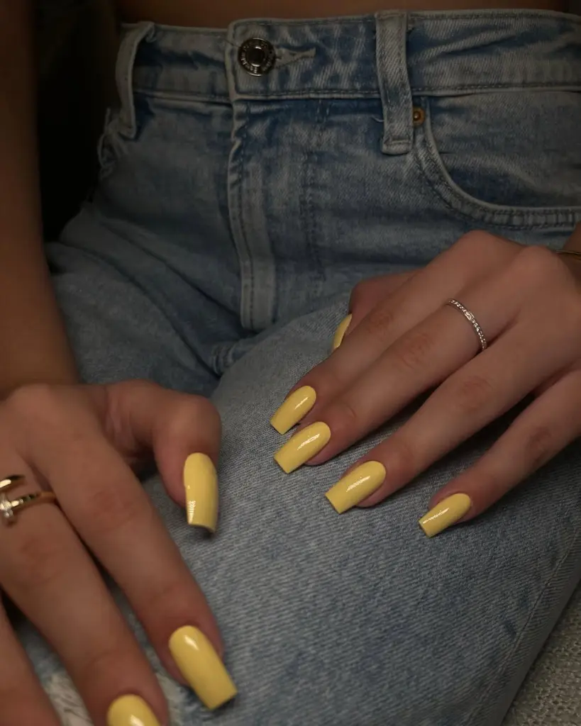 Square summer nails with glossy pastel yellow polish in medium length
