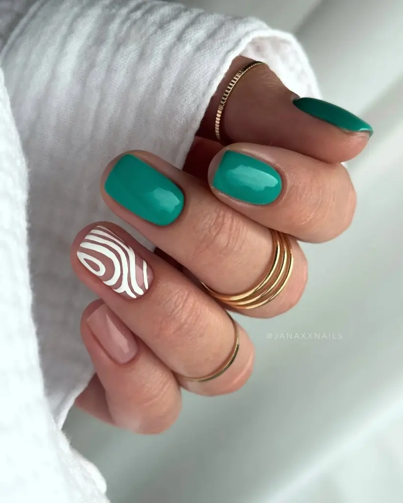 Short summer nails with glossy teal green polish on most nails, white abstract swirl pattern on accent nail, and neutral nude on pinky