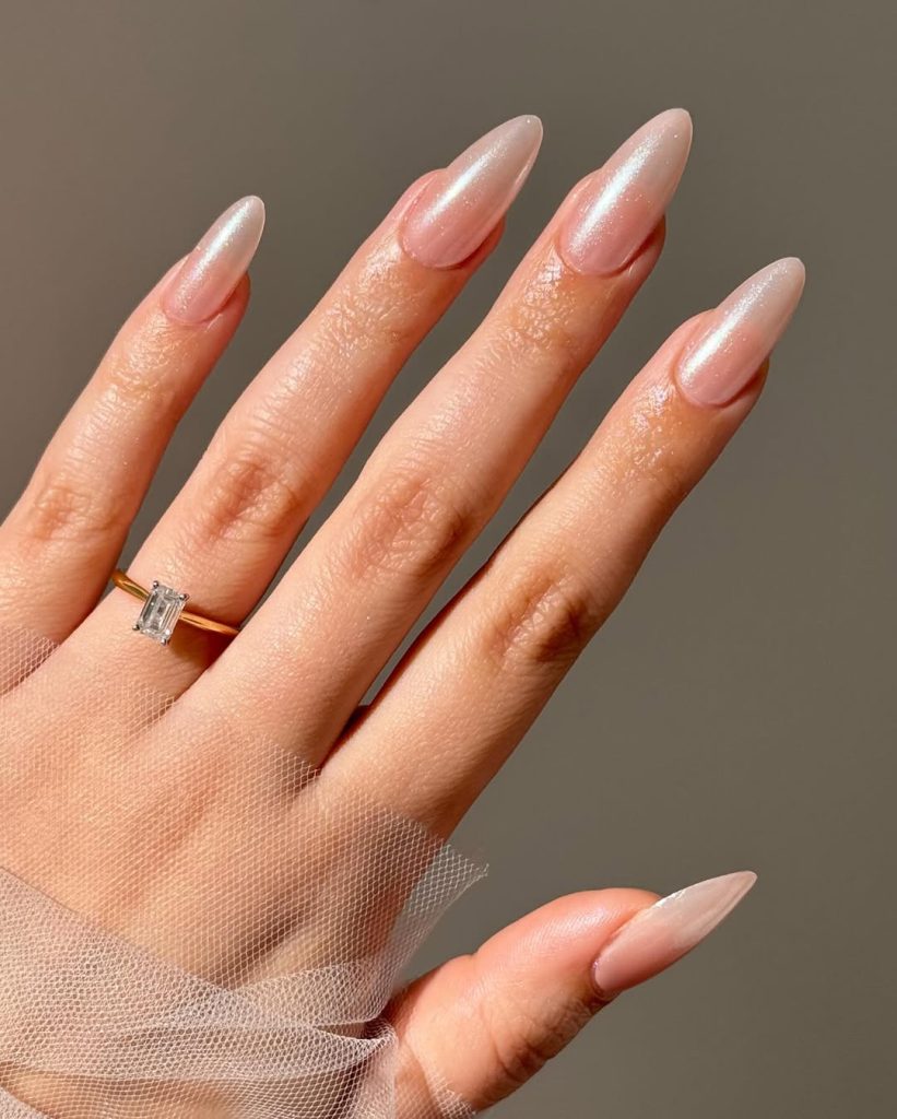 Almond-shaped minimalist nails with soft pink base and pearlescent shimmer finish
