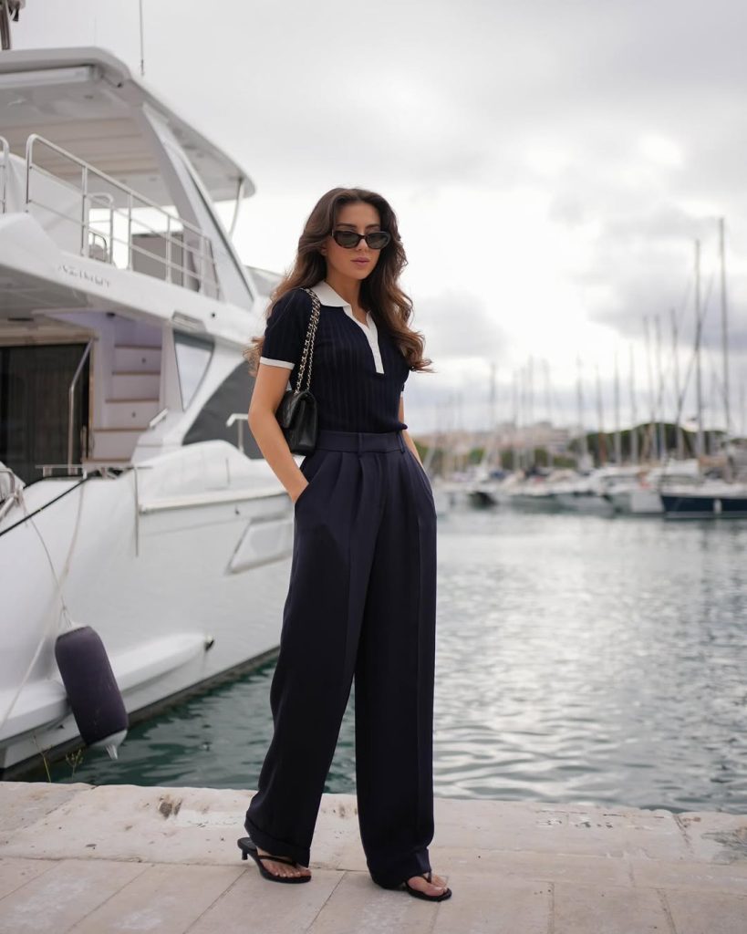  Nautical European vacation outfit with navy contrast-collar polo top, wide-leg pleated trousers, quilted chain shoulder bag and black kitten heels 