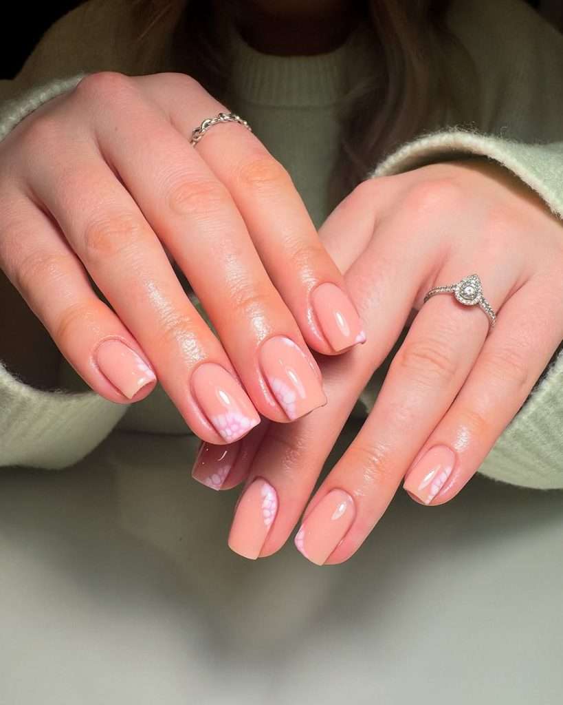 Square spring nails with peachy pink polish and subtle white daisy design on tips

