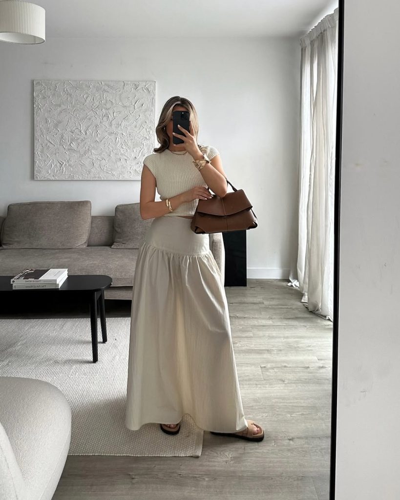 Summer outfit with cream ribbed cap sleeve top, matching cream flowy maxi skirt, brown leather handbag and simple flat sandals
