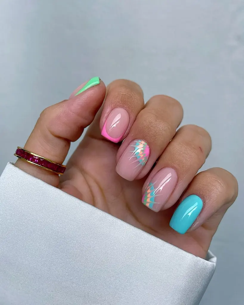 Short summer nails with nude pink base featuring pink French tips, colorful tie-dye pattern in blue and peach, bright turquoise accent nail and neon green corner detail