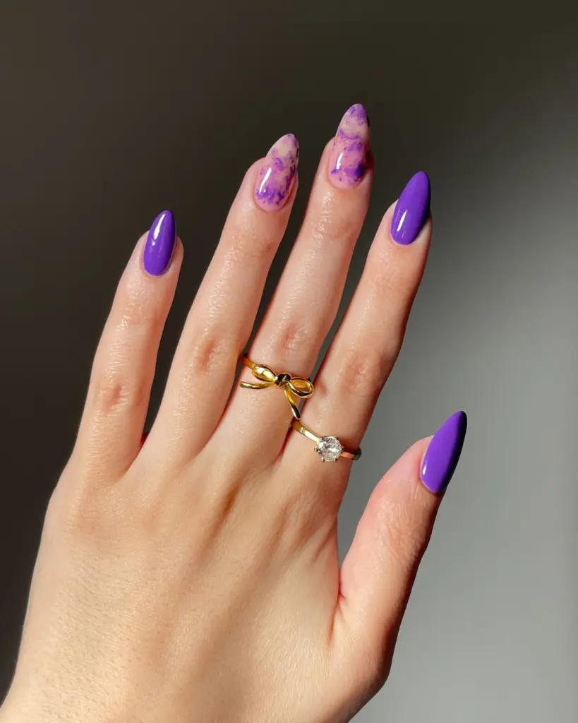 Almond summer nails with solid purple polish and pink-purple watercolor marble design accent nails