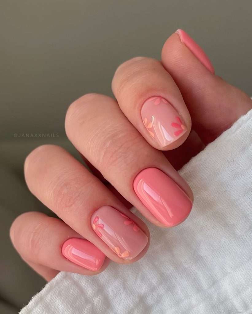 Short spring nails with alternating sheer pink and coral polish with small floral accents
