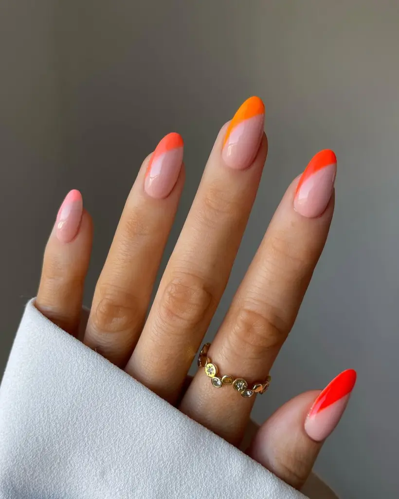 Almond summer nails with sheer pink base and asymmetrical side tips in coral, orange and red shades