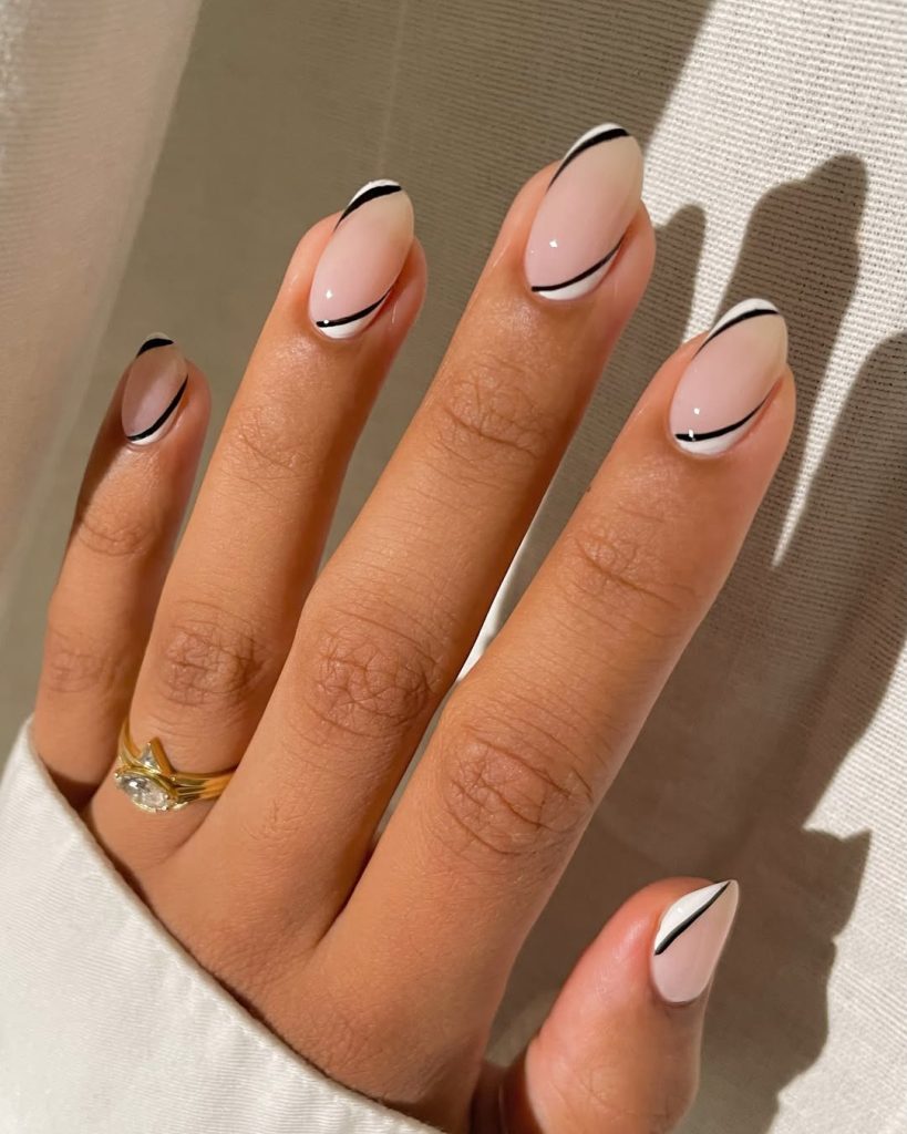 Almond-shaped minimalist nails with pale pink base and thin black and white diagonal line accents at both tips and cuticle area