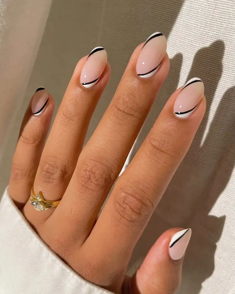 Almond-shaped minimalist nails with pale pink base and thin black and white diagonal line accents at both tips and cuticle area