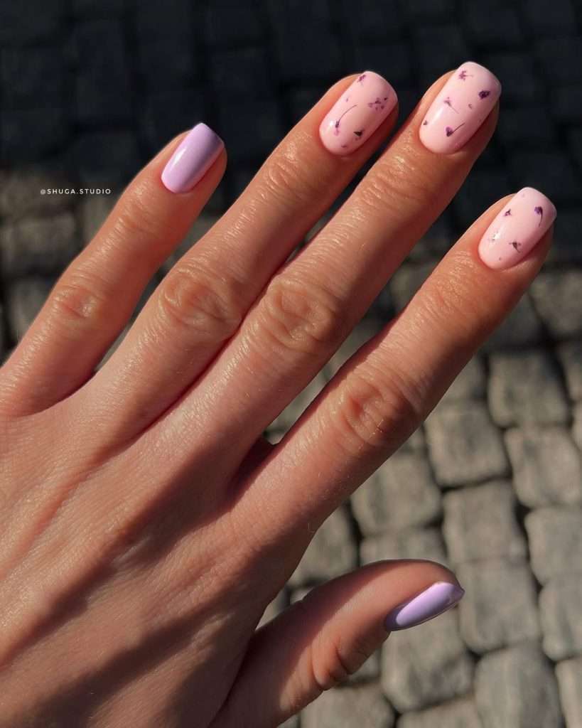 Short square nails in pink and lilac with pressed purple dried flowers on accent nails