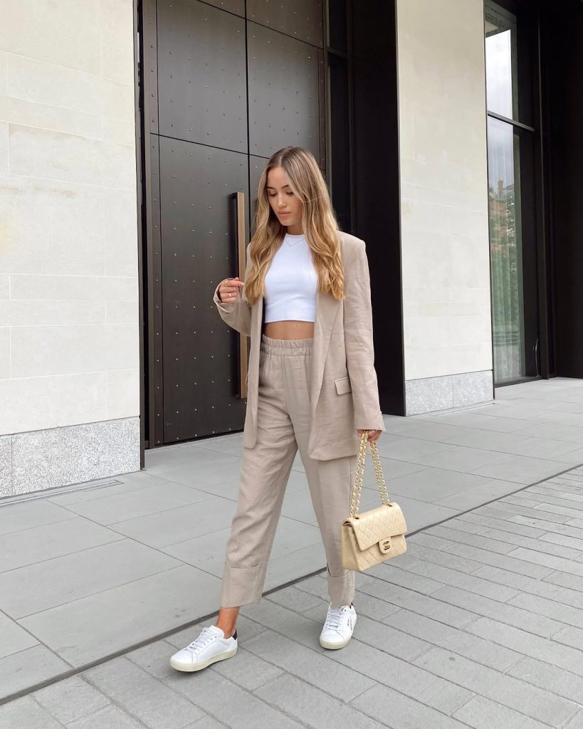 Elegant casual outfit with beige linen blazer, matching linen pants, white crop top, designer crossbody bag and white sneakers