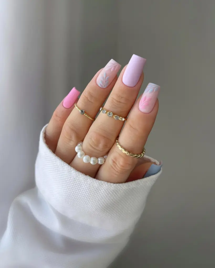 Square summer nails with pink and lilac bases featuring delicate blue and pink leaf designs
