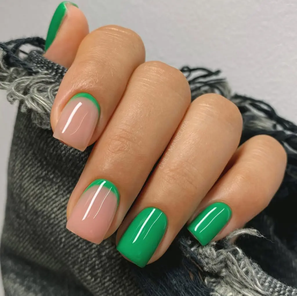 Short square nails featuring bright green polish on accent nails and nude base with green outline