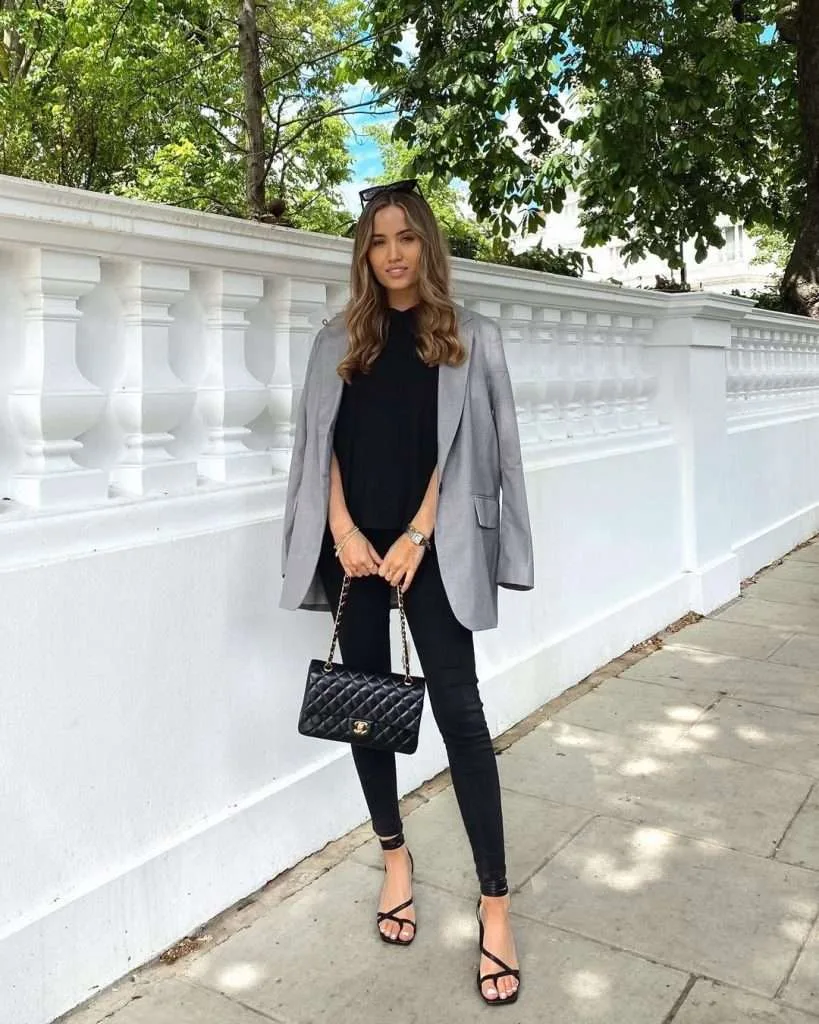 Classy spring date night outfit with gray oversized blazer, black top, skinny jeans, strappy sandals and designer quilted handbag
