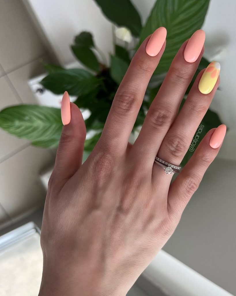 Almond summer nails with matte coral polish and one yellow accent nail with orange swirl design