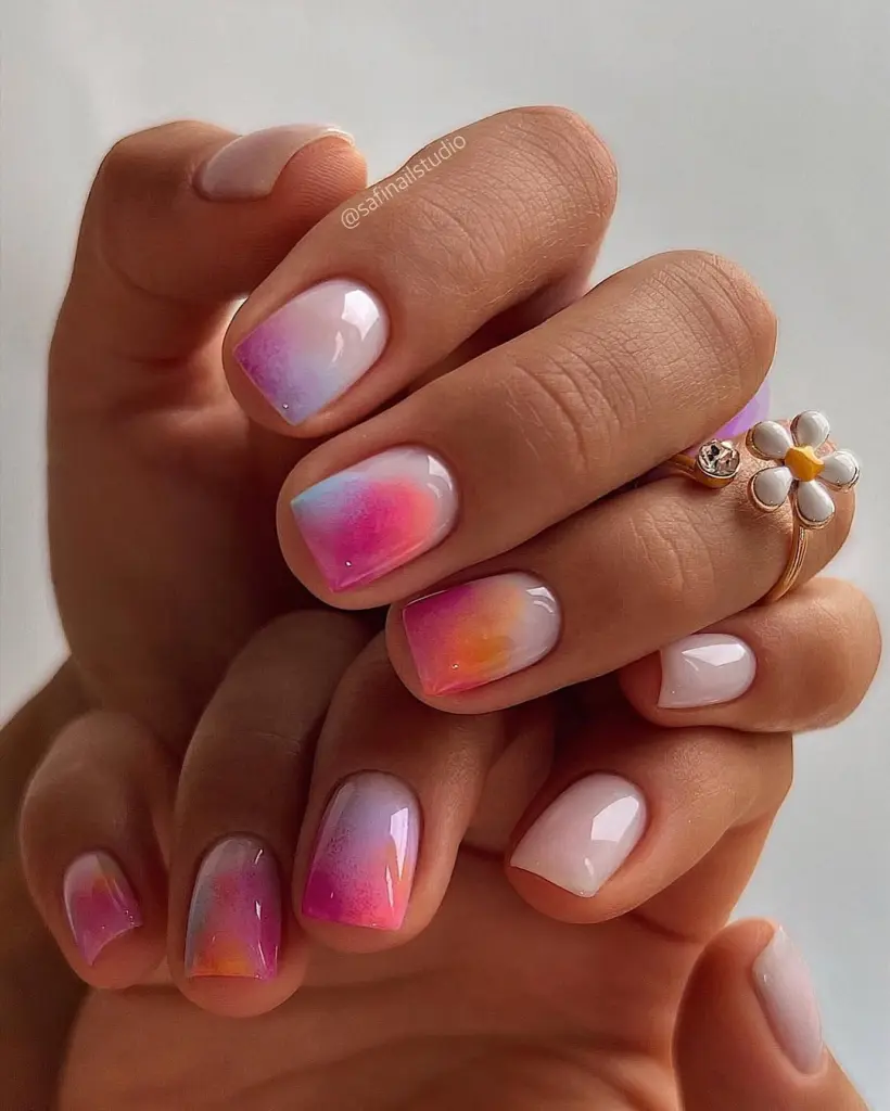 Short summer nails with watercolor gradient effect in pink, orange, purple and blue hues on most nails with clean white accent nails