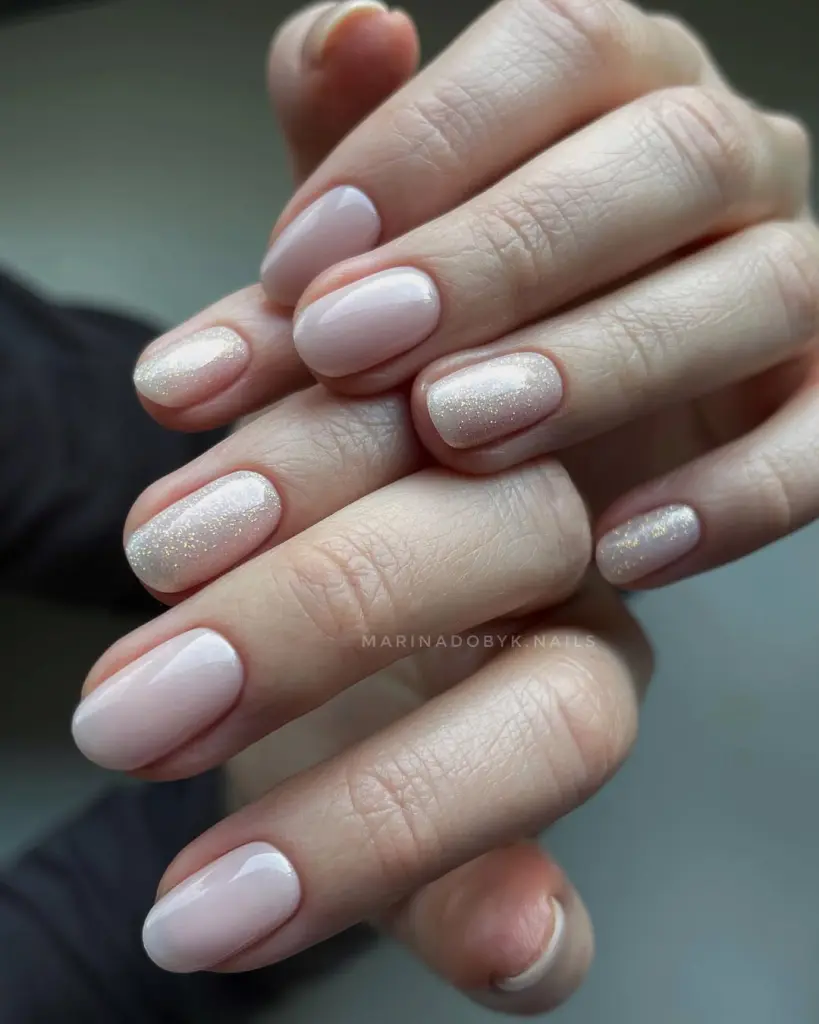 short round minimalist nails with milky pink base and alternating iridescent shimmer accents nails