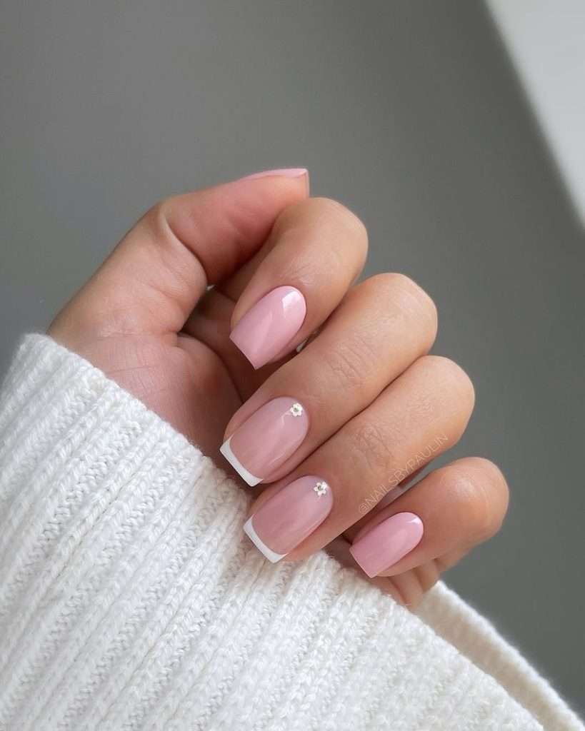Short square nails with pink base, white French tips and small daisy accents