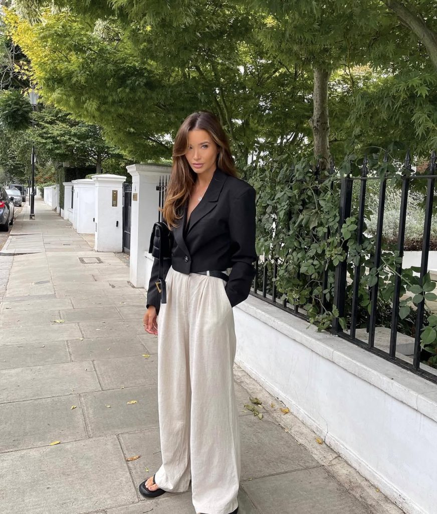 classy outfit with cropped black blazer, cream wide-leg linen pants, black shoulder bag and black flip flops