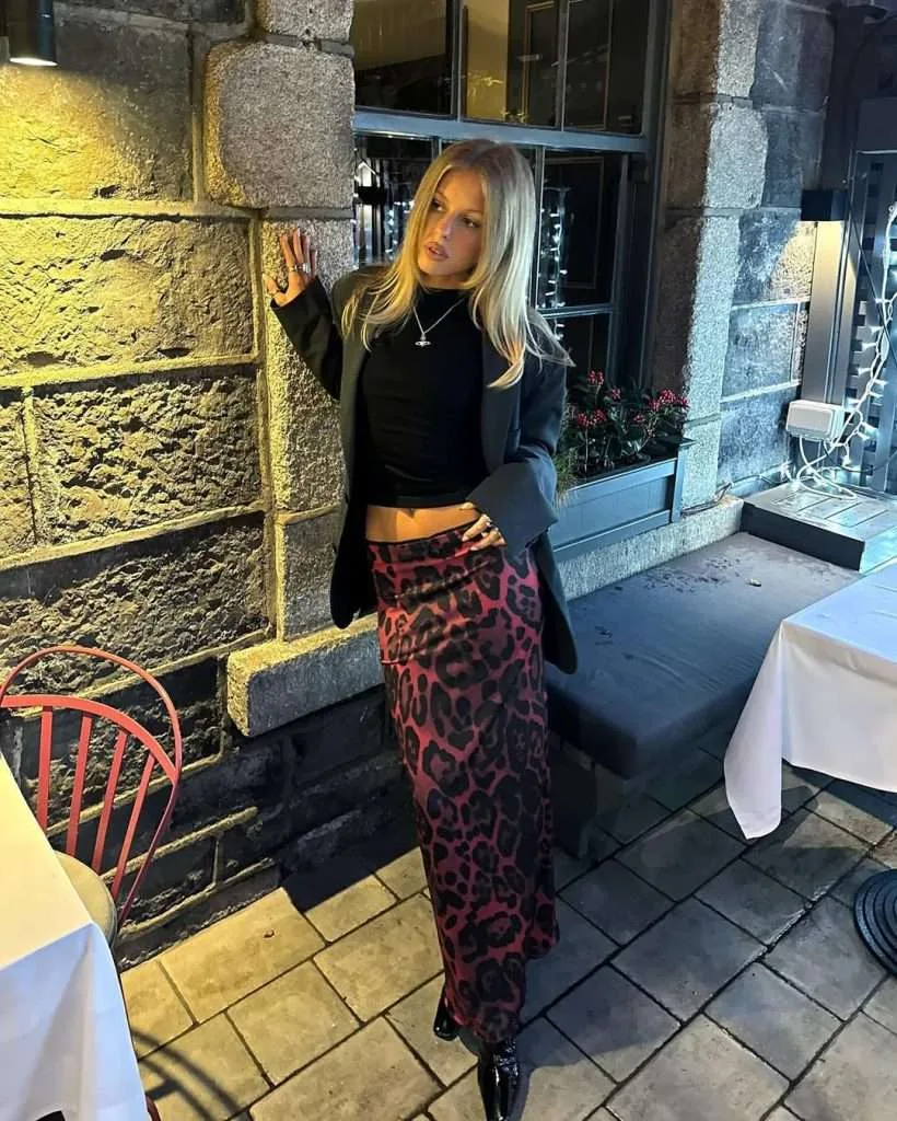 Edgy spring date night outfit with black blazer, black crop top, red leopard print maxi skirt and black boots
