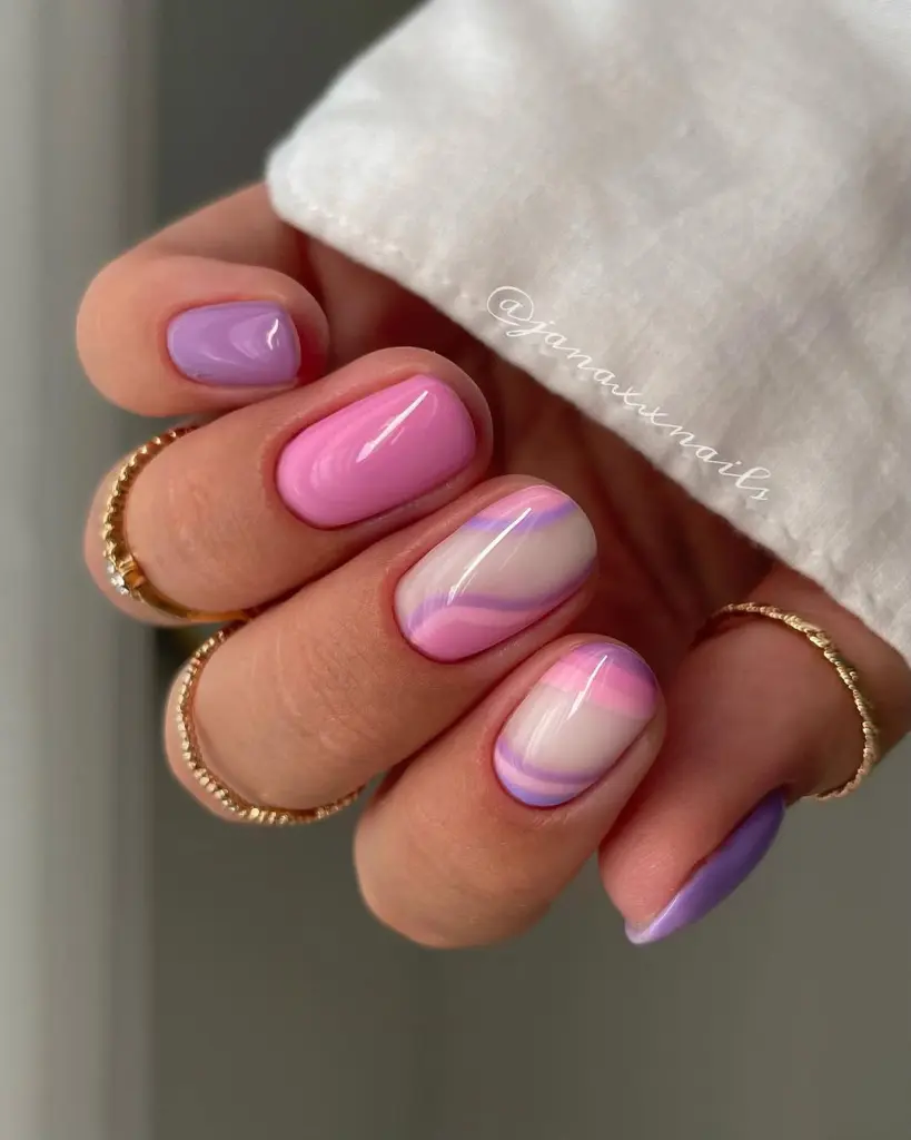 Short summer nails with glossy pink and purple polish featuring abstract wave designs
