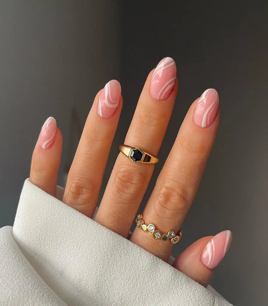 Almond summer nails with light pink base and white abstract swirl pattern designs
