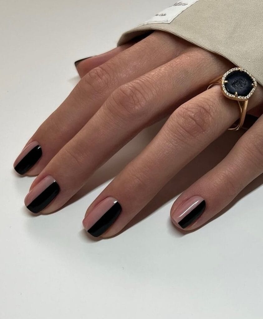 Short square minimalist nails with glossy black polish and one clear nude accent nail