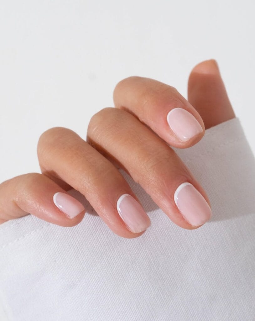 Short square minimalist nails with natural pink base and ultra-subtle white reverse French line at cuticle