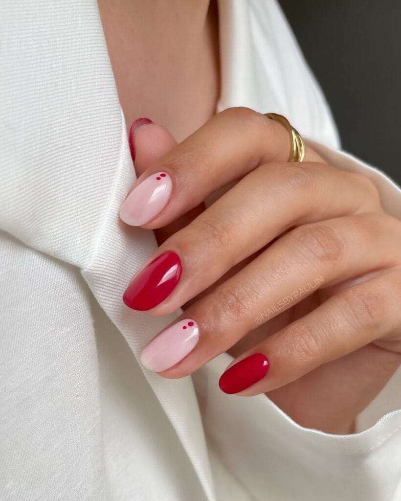 Short oval minimalist nails alternating glossy red solid and milky pink with two small red dot accents