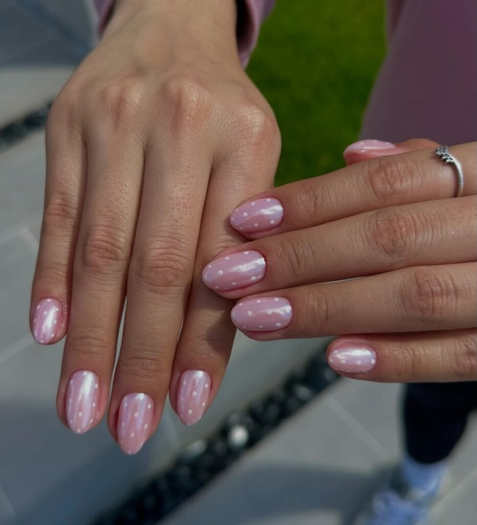 Short oval minimalist nails with soft pink base and white polka dot accents throughout