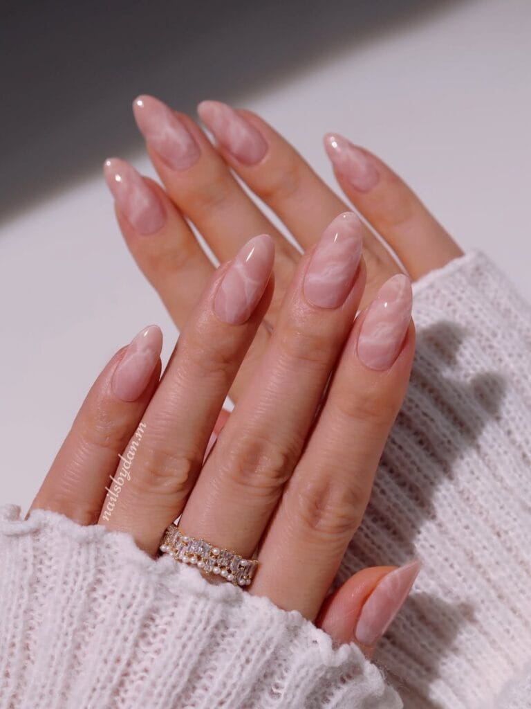 Almond minimalist nails with nude pink base and subtle white marble swirl pattern