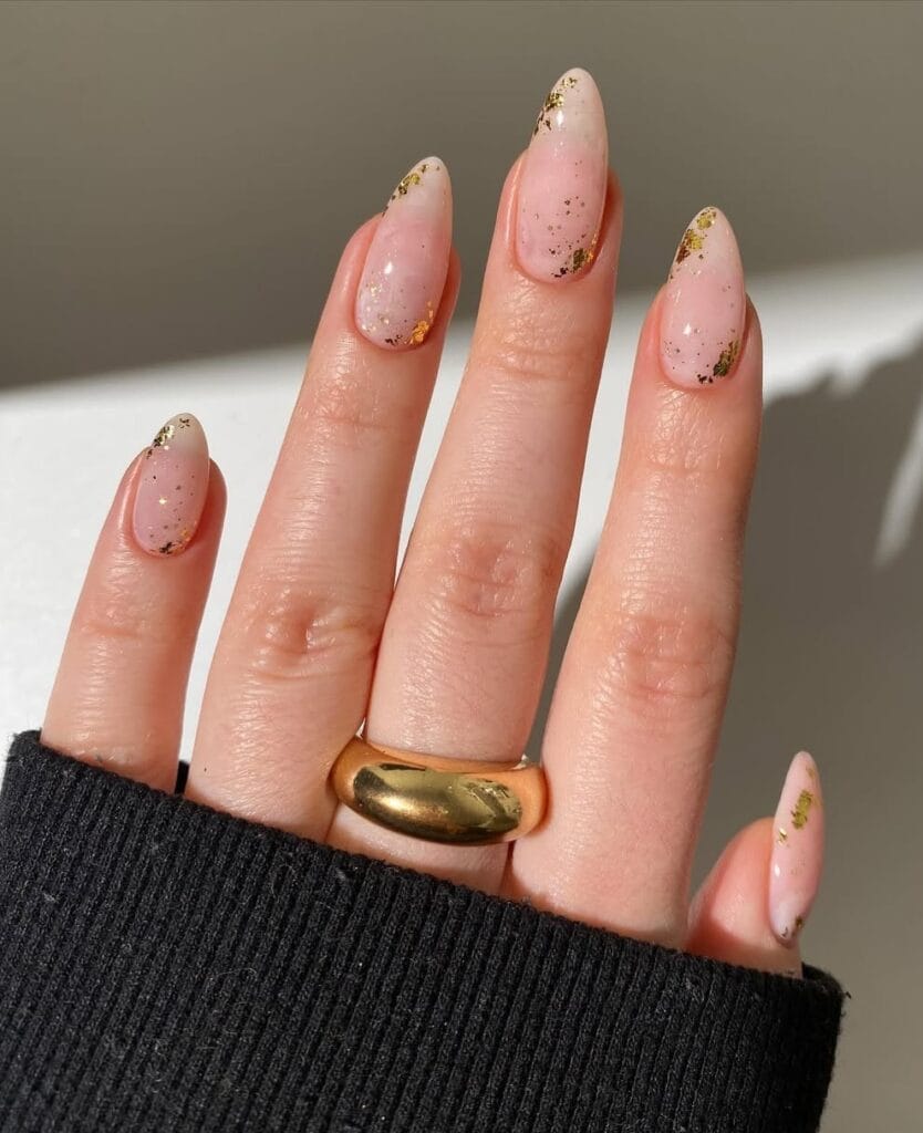 Almond minimalist nails with sheer pink base and scattered gold foil flecks throughout