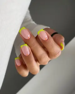 hort summer nails with bright neon yellow French tips and small orange dot accents on pink nail bed