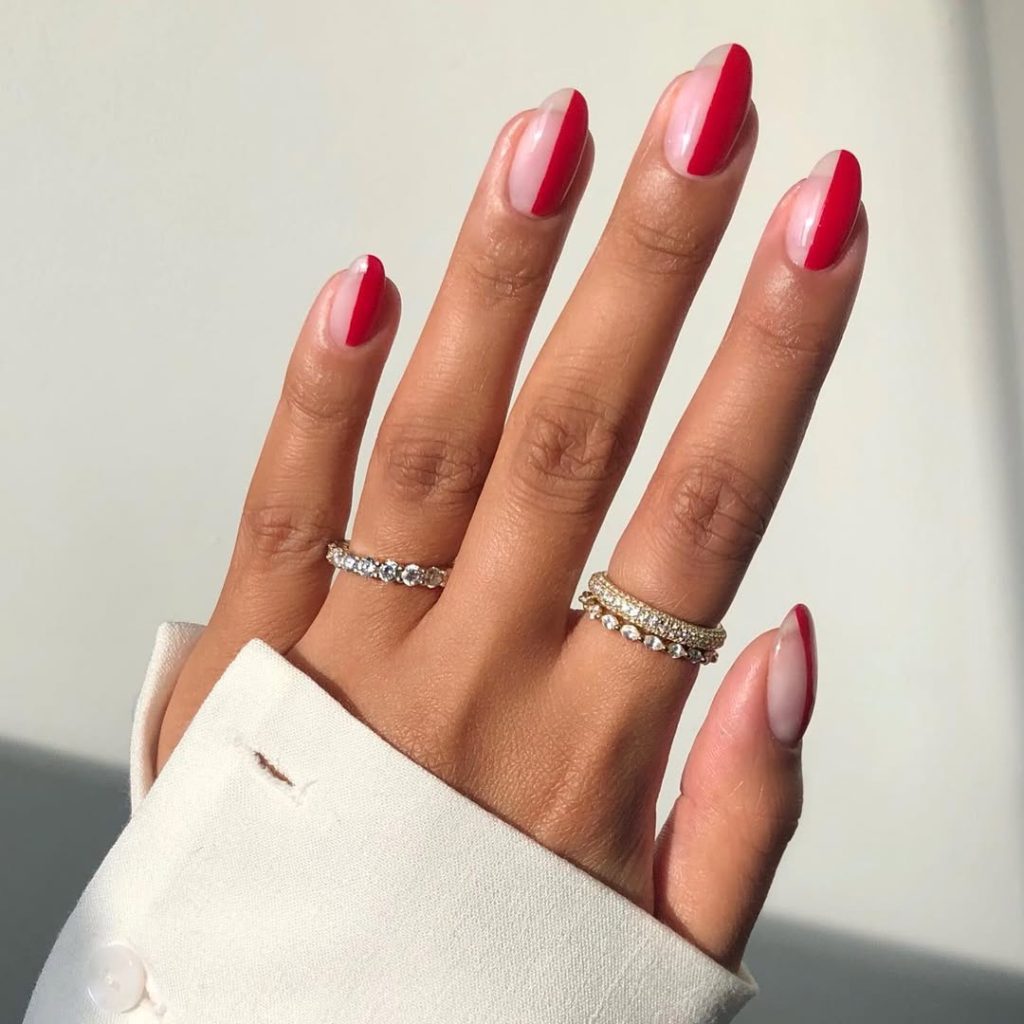 Almond shaped nails with diagonal split design featuring half red and half natural pink polish
