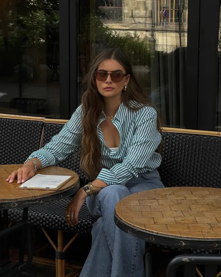 Casual summer outfit with green and white striped button-down shirt, relaxed fit medium blue jeans, brown sunglasses and green Nike sneakers
