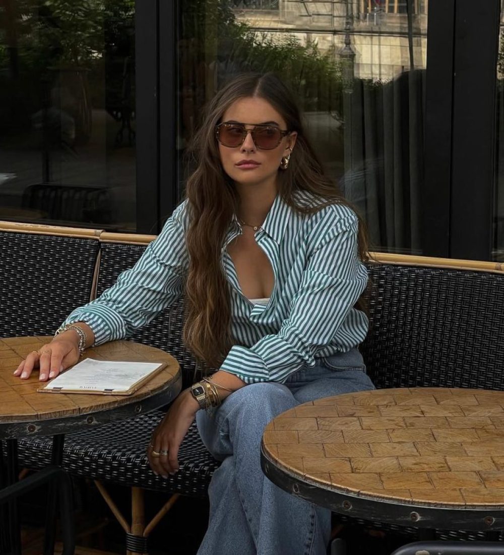 Casual summer outfit with green and white striped button-down shirt, relaxed fit medium blue jeans, brown sunglasses and green Nike sneakers