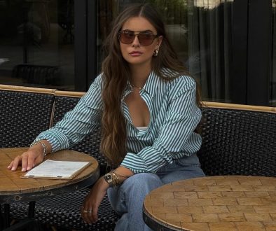 Casual summer outfit with green and white striped button-down shirt, relaxed fit medium blue jeans, brown sunglasses and green Nike sneakers