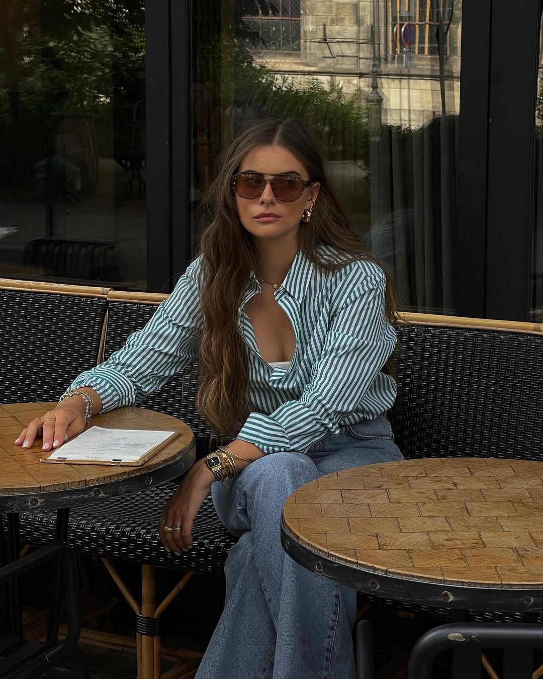 Casual summer outfit with green and white striped button-down shirt, relaxed fit medium blue jeans, brown sunglasses and green Nike sneakers